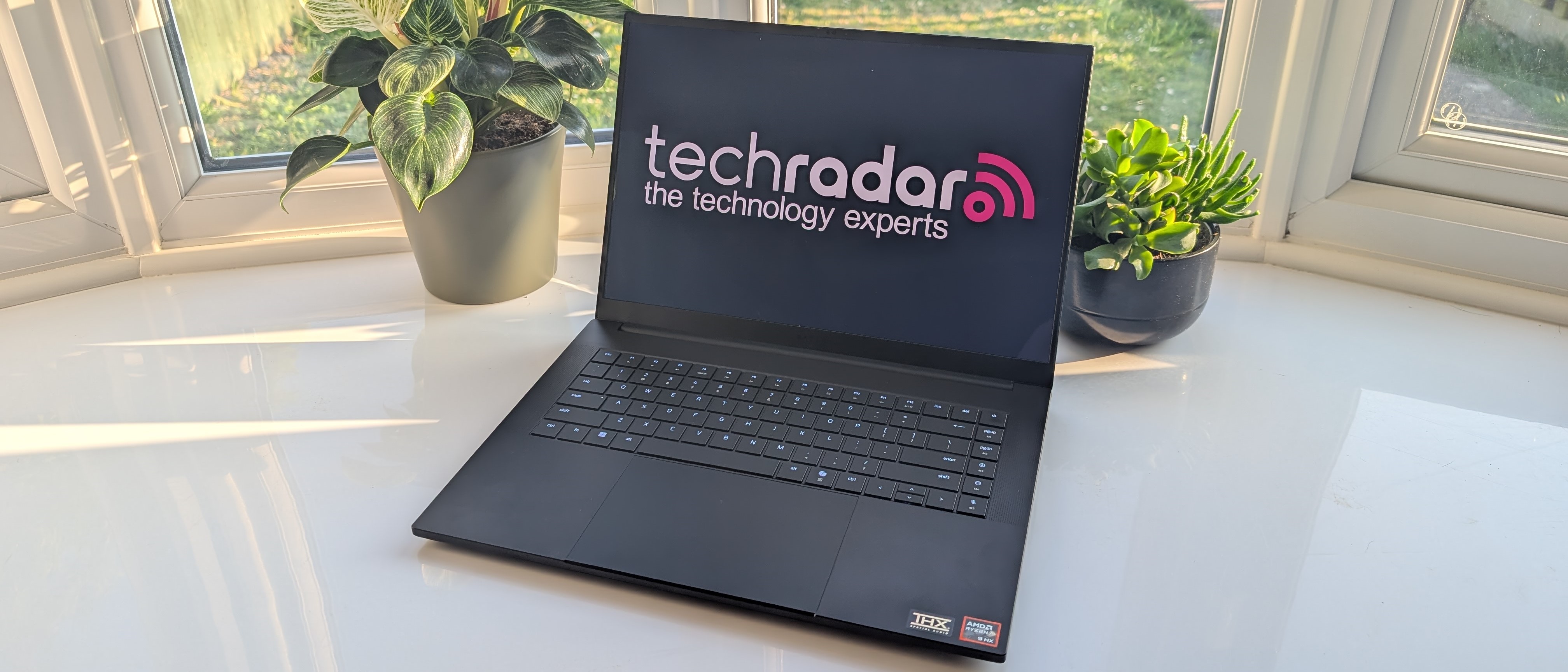 The Razer Blade 16 photographed for TechRadar on a white surface with plants in the background.