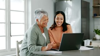 Older woman and younger woman looking happy in front of a laptop