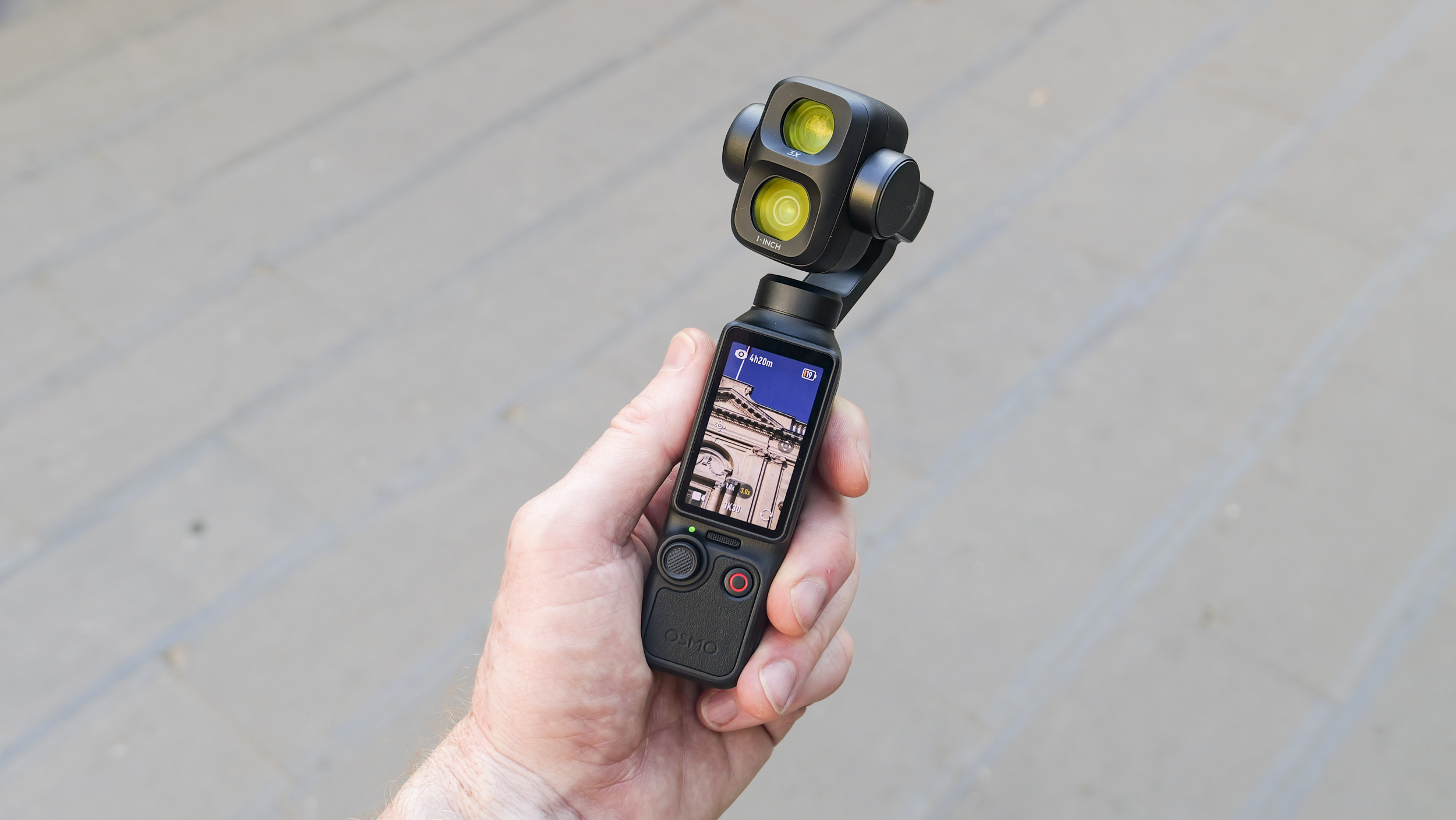 DJI Osmo Pocket 4P vlogging camera in a person's hand in a city street, screen vertical