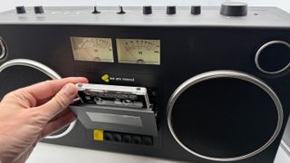 An man inserts a tape into the We Are Rewind GB-001 boombox