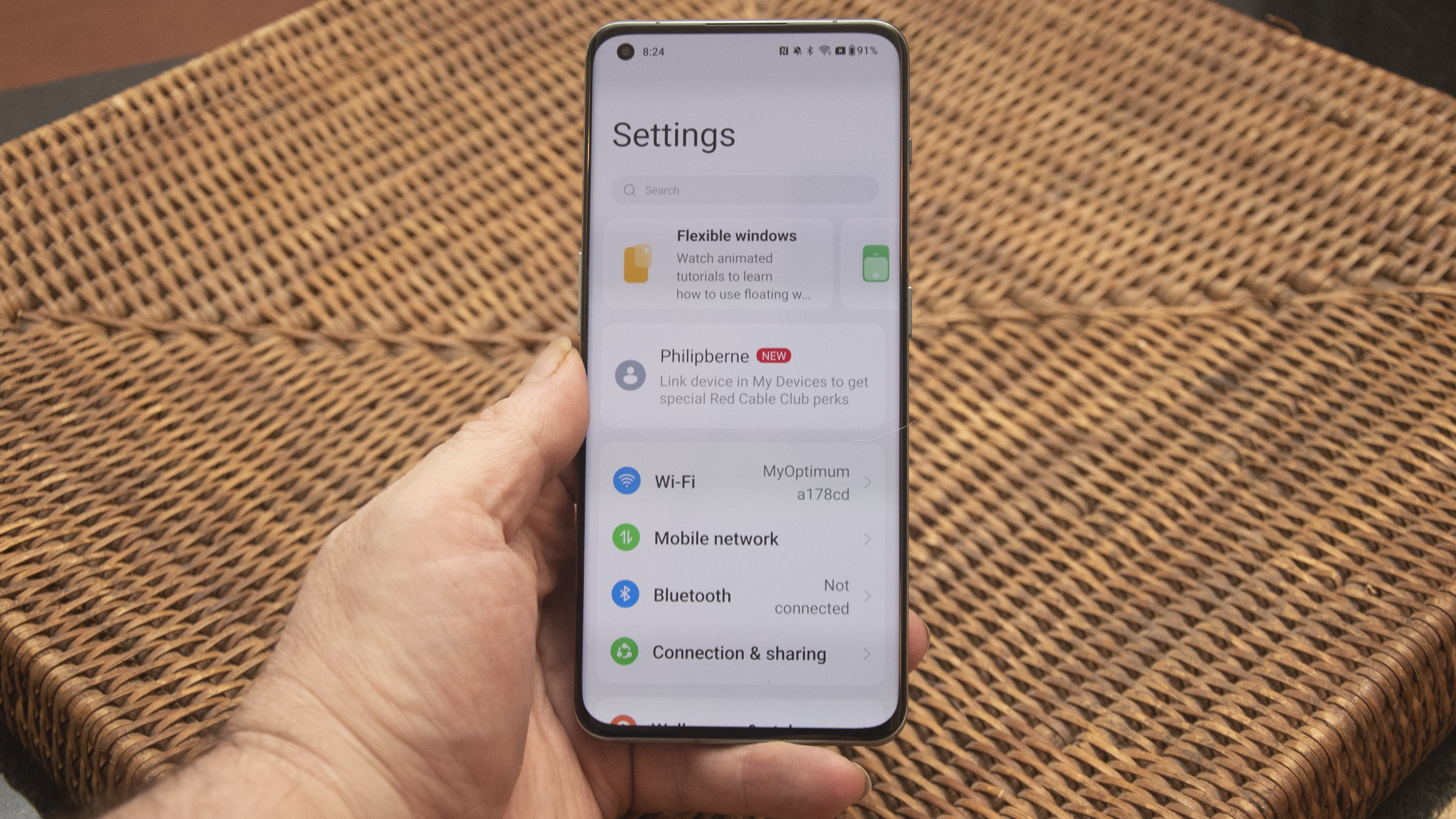 OnePlus 11 in green on wicker basket top with screen on