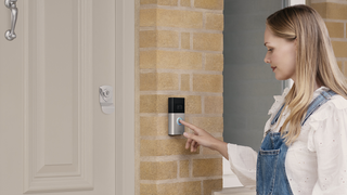 A woman uses a Ring doorbell on the outside of a house