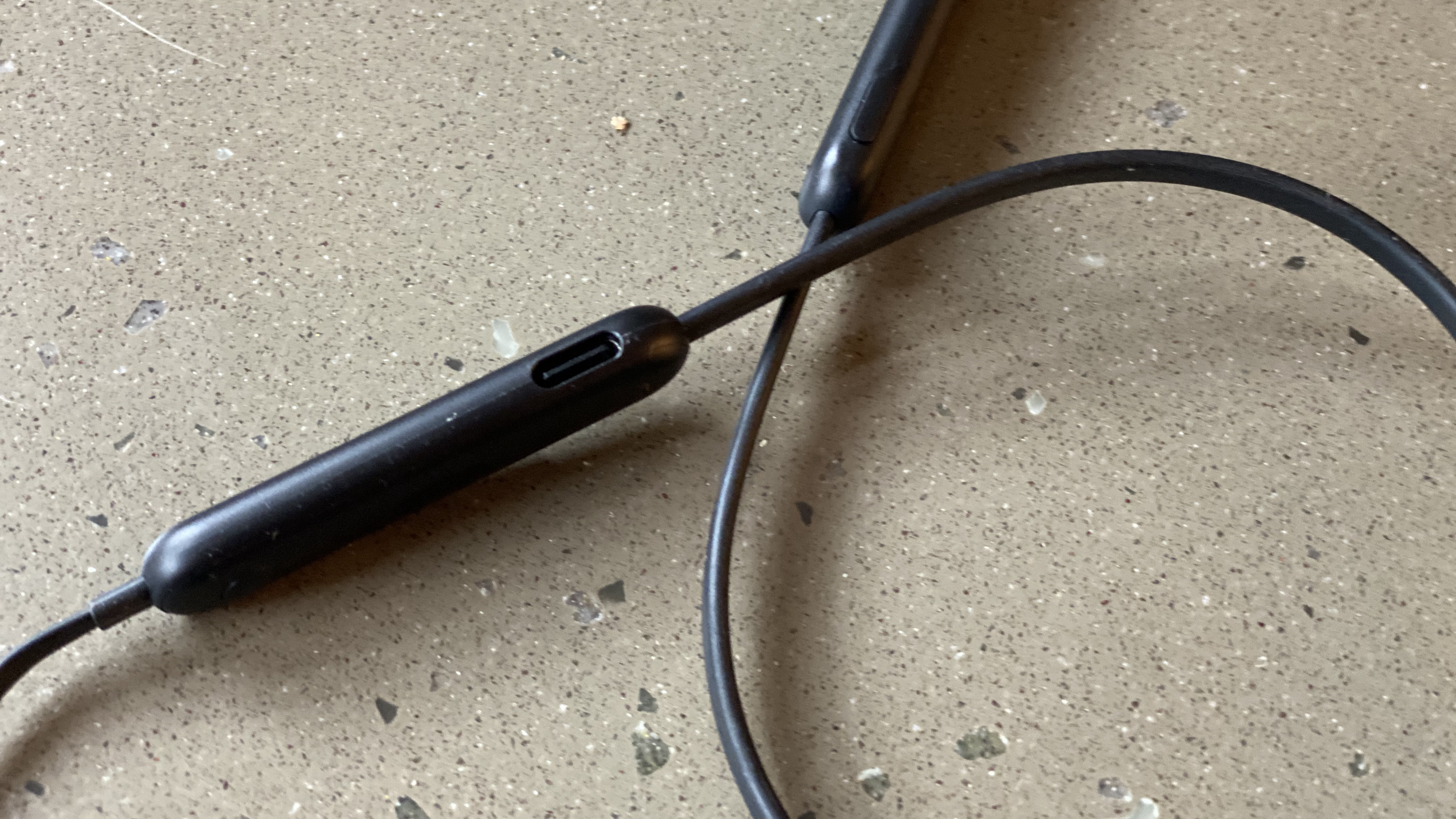 The controls of the Beats Flex wireless earphones in black on a marble surface