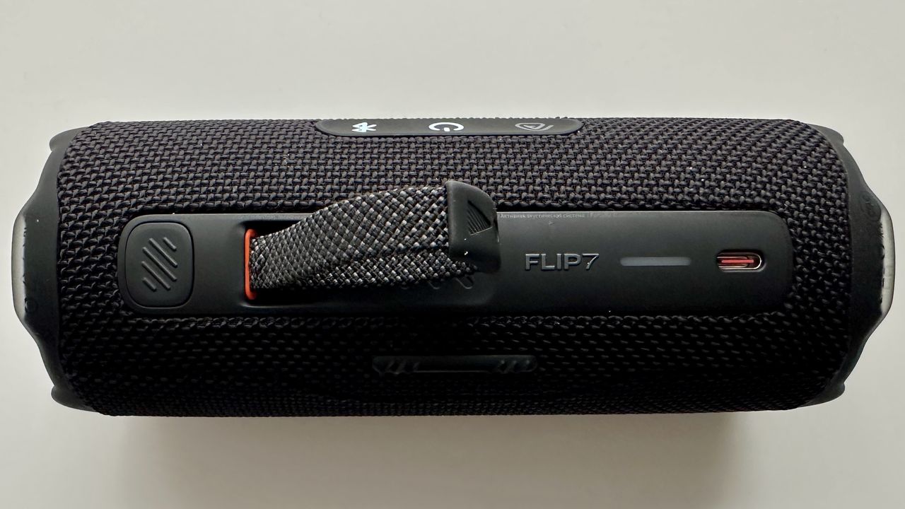 Carry strap of the JBL Flip 7 portable Bluetooth speaker, on a white surface
