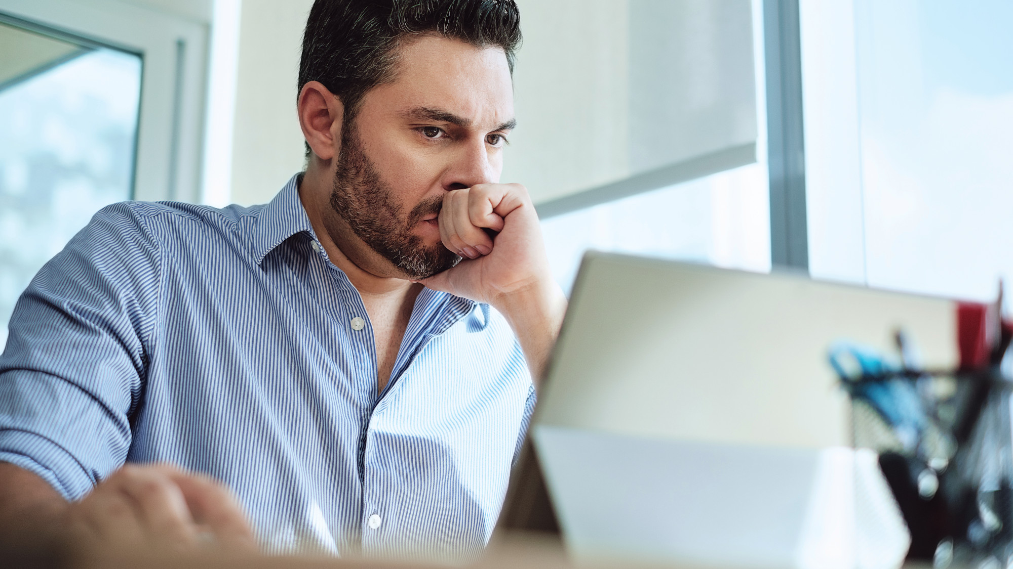 Person using a laptop looking thoughtful
