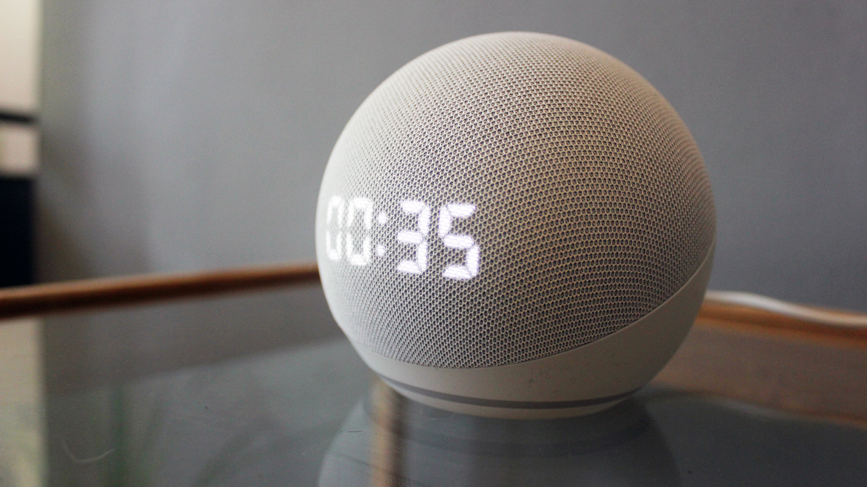 the amazon echo dot with clock pictured on a glass table
