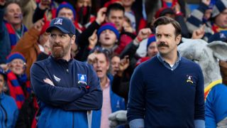 Coach Beard and Ted look at someone off-camera in Ted Lasso on Apple TV Plus