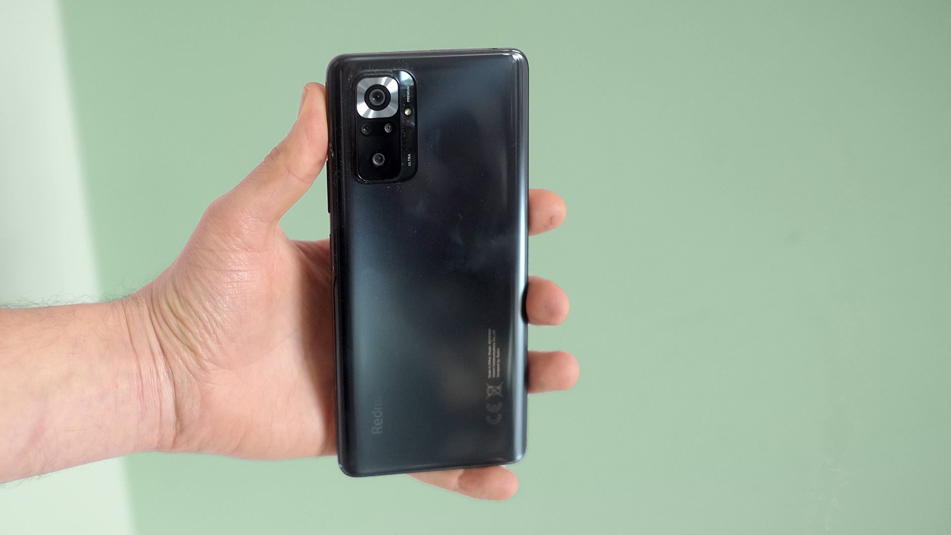 A Xiaomi Redmi Note 10 Pro in someone's hand, from the back