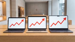 The Apple MacBook Neo, Air and Pro on a bench with price rise logos showing on screen