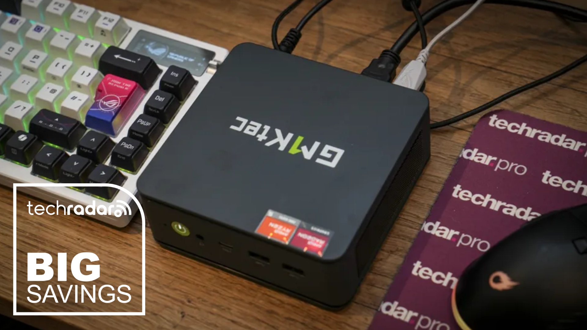 The GMKtecc M6 Ultra on a desk during our review, next to a white TechRadar badge in the lower left corner that reads 'Big Savings'