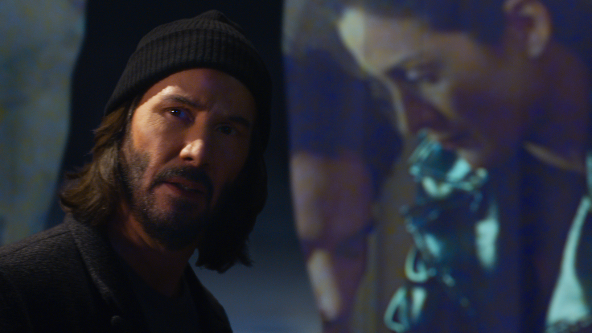 Keanu Reeves' Neo standing next to a flashback scene in The Matrix Resurrections
