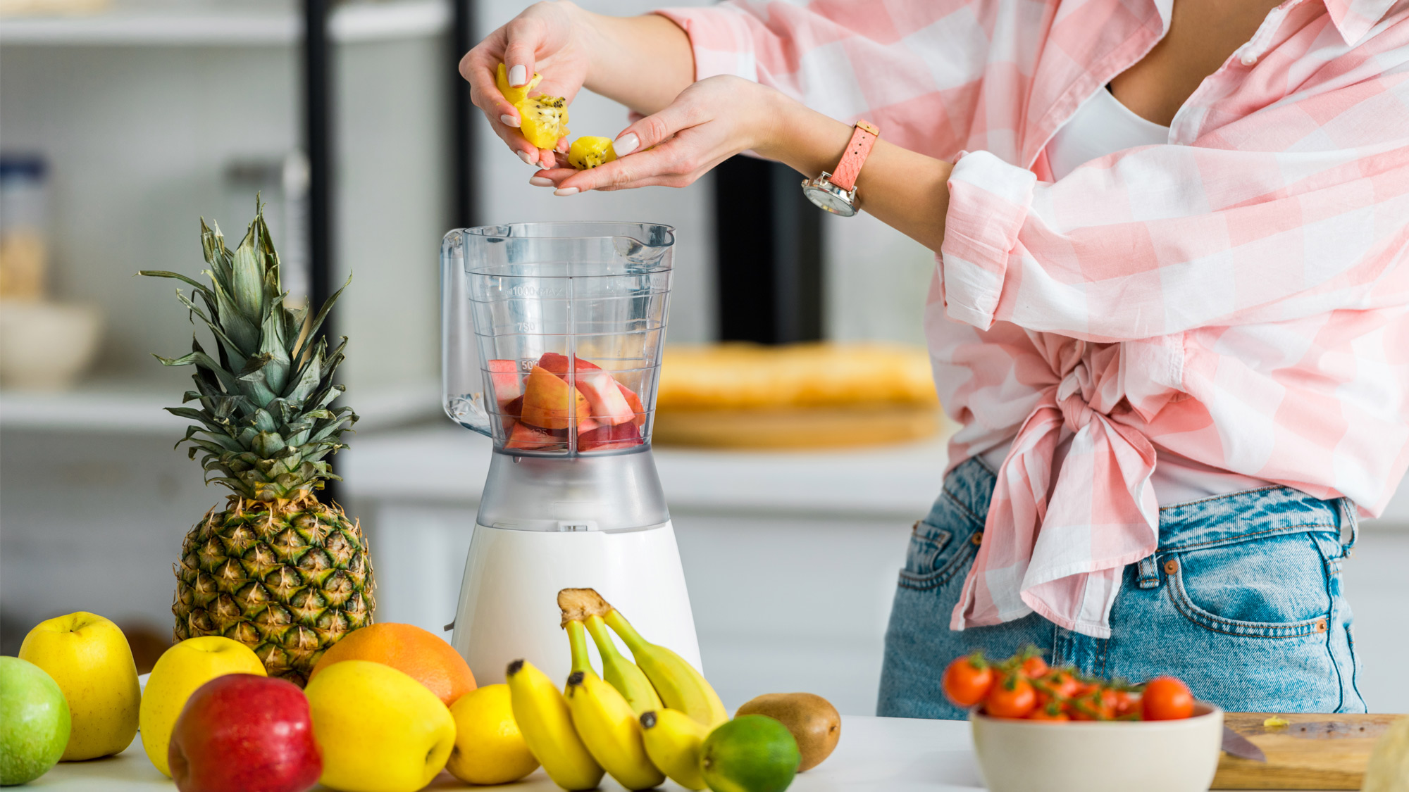 Woman adding fruit to a blender