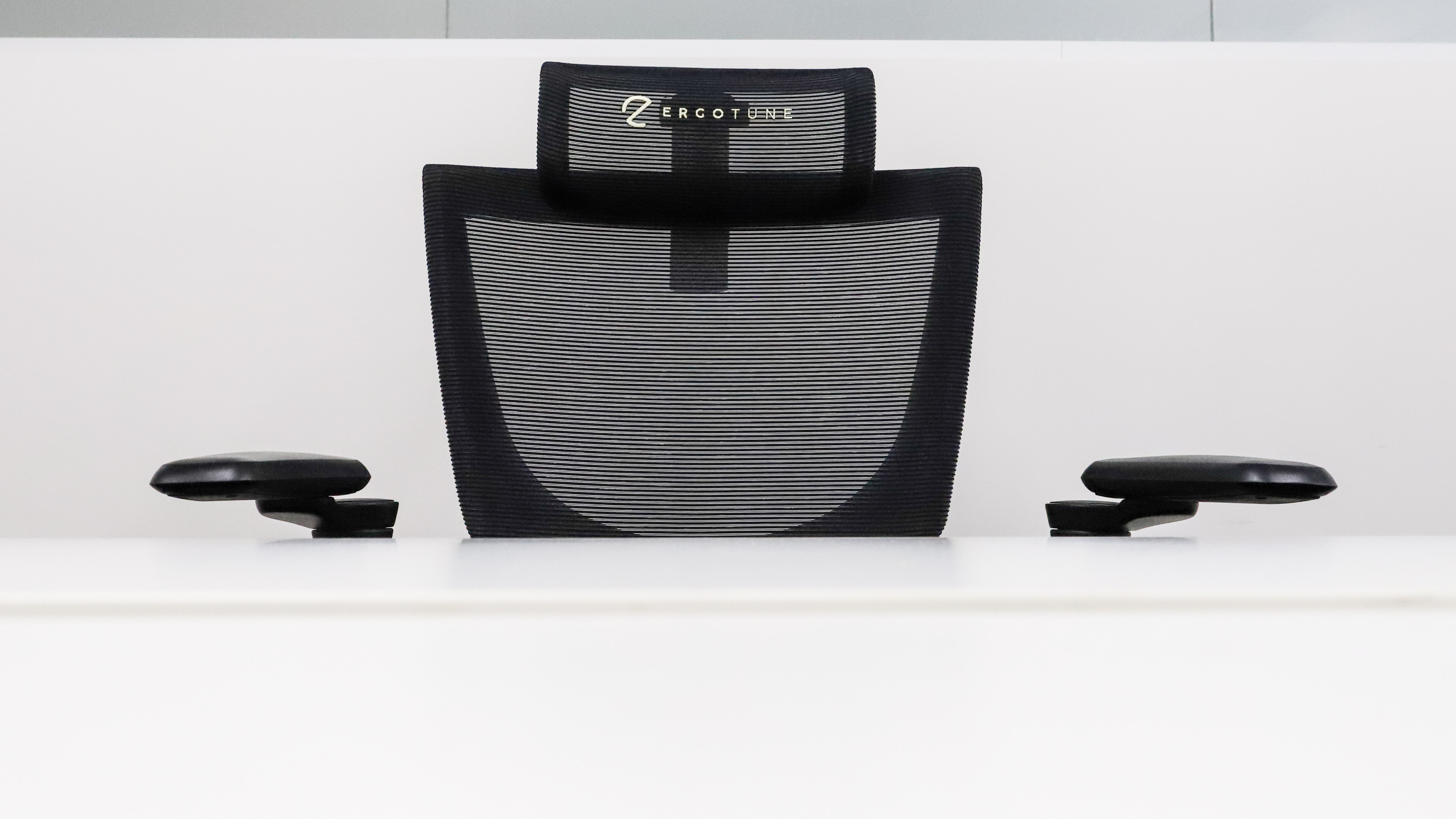 The backrest of the ErgoTune Supreme V3 behind a white desk