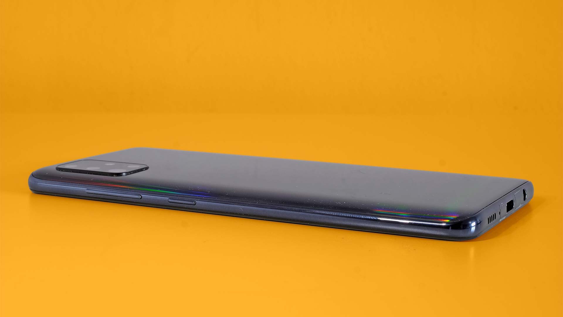 A Samsung Galaxy A51 from the side, against an orange background