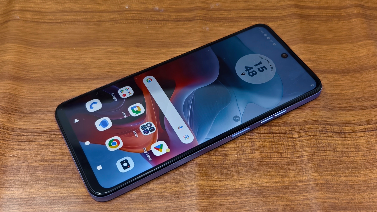 The Moto G34 laying face up on a wooden surface