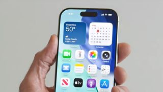 A person holding an iPhone running iOS 26.