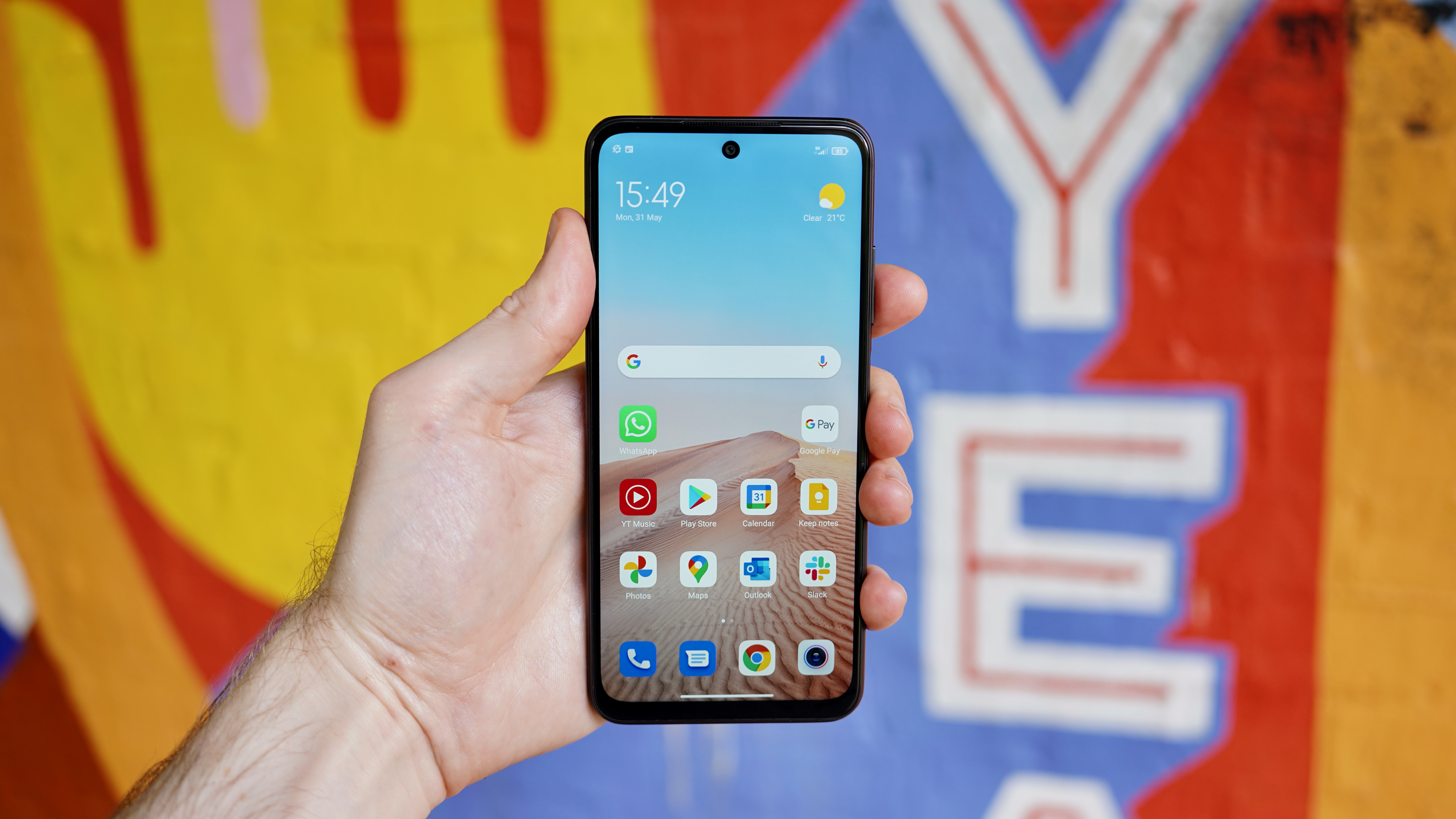 A Xiaomi Redmi Note 10 5G in someone's hand, with the screen on