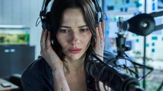 Lily Sullivan listens to someone on headphones in Monolith