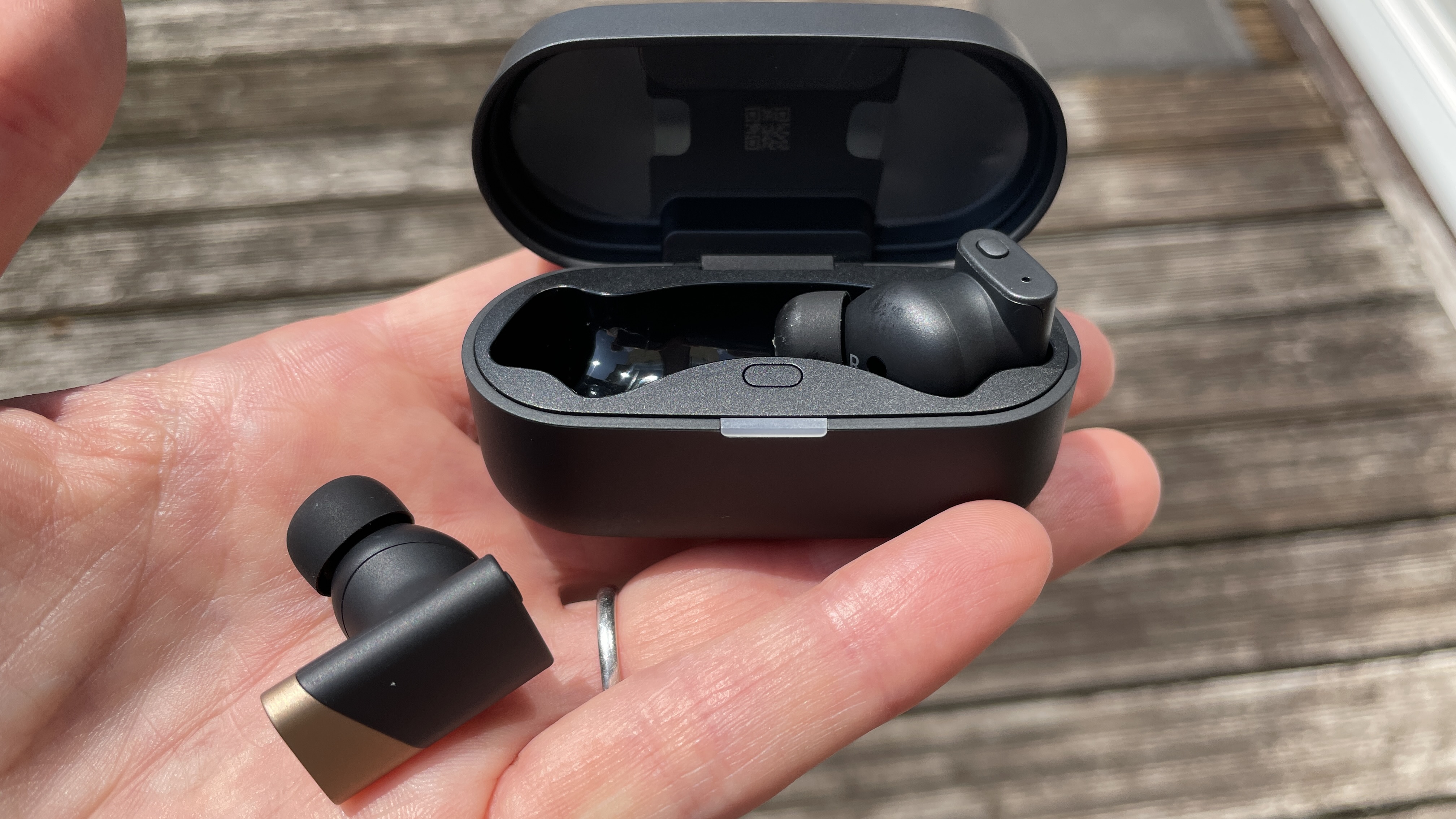 Status Audio Pro X GoldenSound, next to AirPods or held in a hand, with gold accents showing