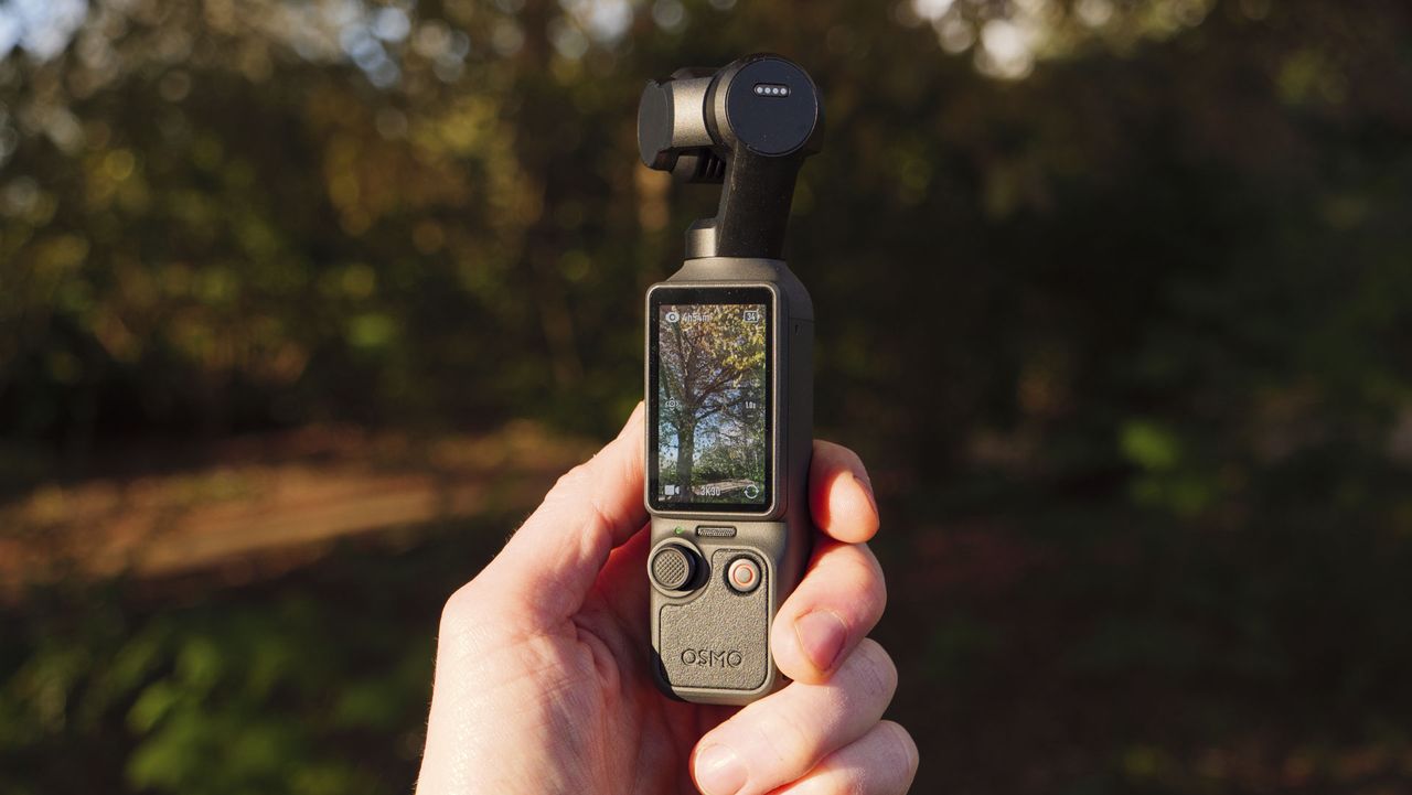 DJI Osmo Pocket 4 vlogging camera in the hand with natural background at golden hour