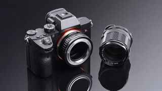 K&F Concept M42 for Sony E-mount vintage lens adapter mounted to a Sony camera on a black background with a reflective surface and a vintage lens placed next to it