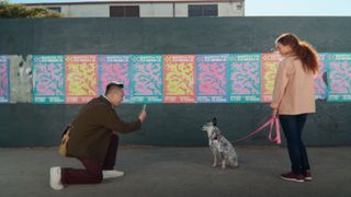 A man kneels to scan a woman's dog with the iPhone 16