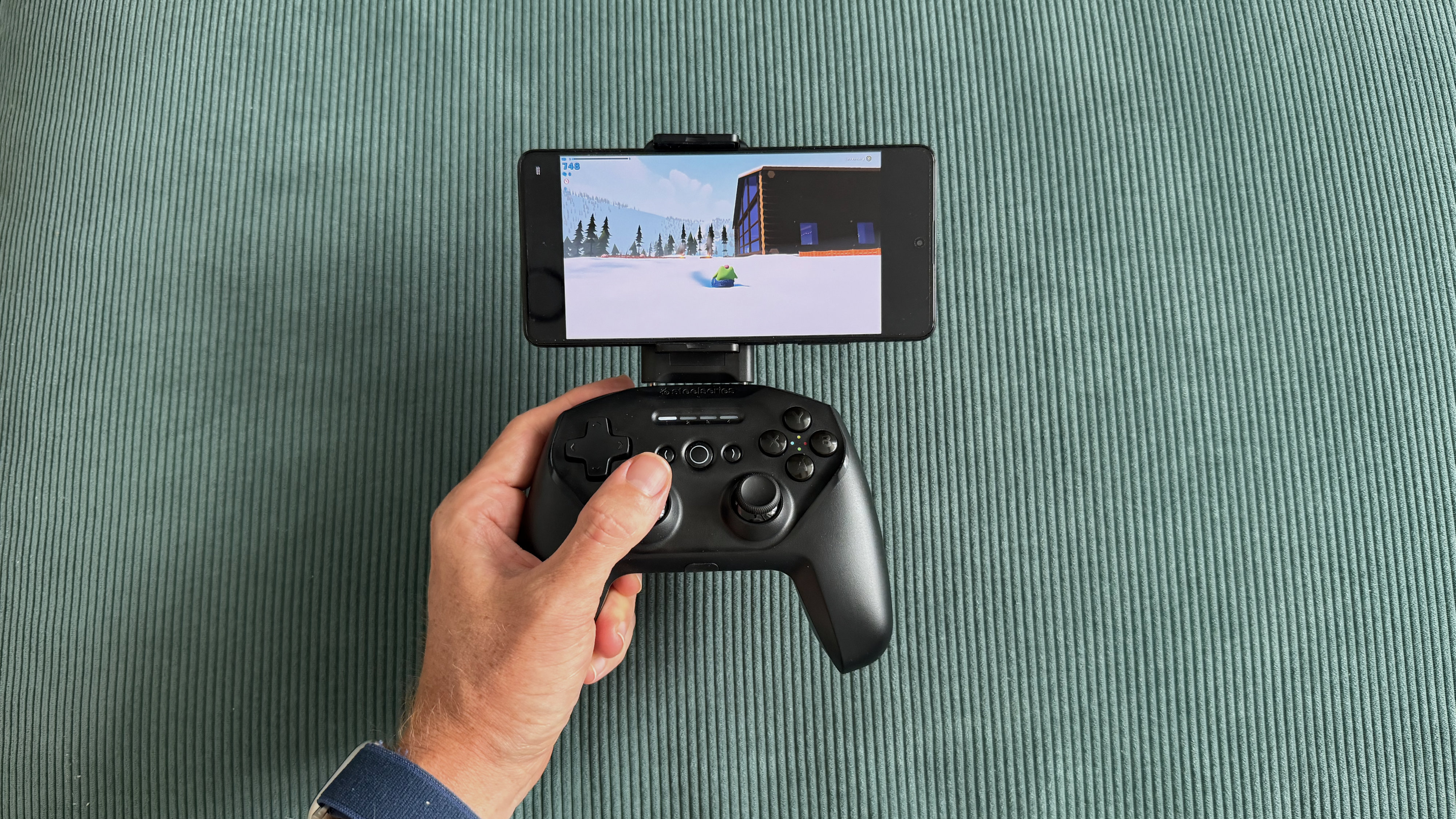 The SteelSeries Stratus+ mobile and PC controller on top of a green carpet surface