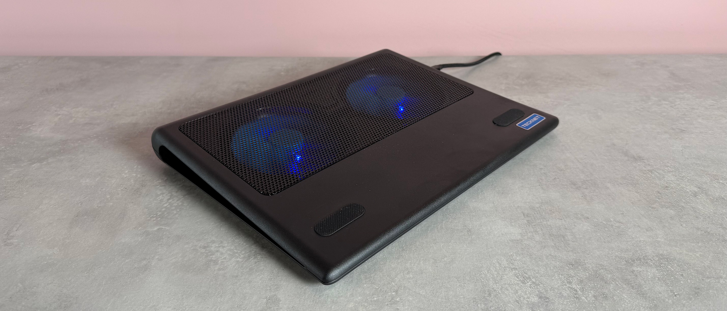The Tecknet N5 Laptop Cooling Pad on a pink background at a 3/4 angle.