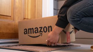 Person picking up Amazon box from their doorstep
