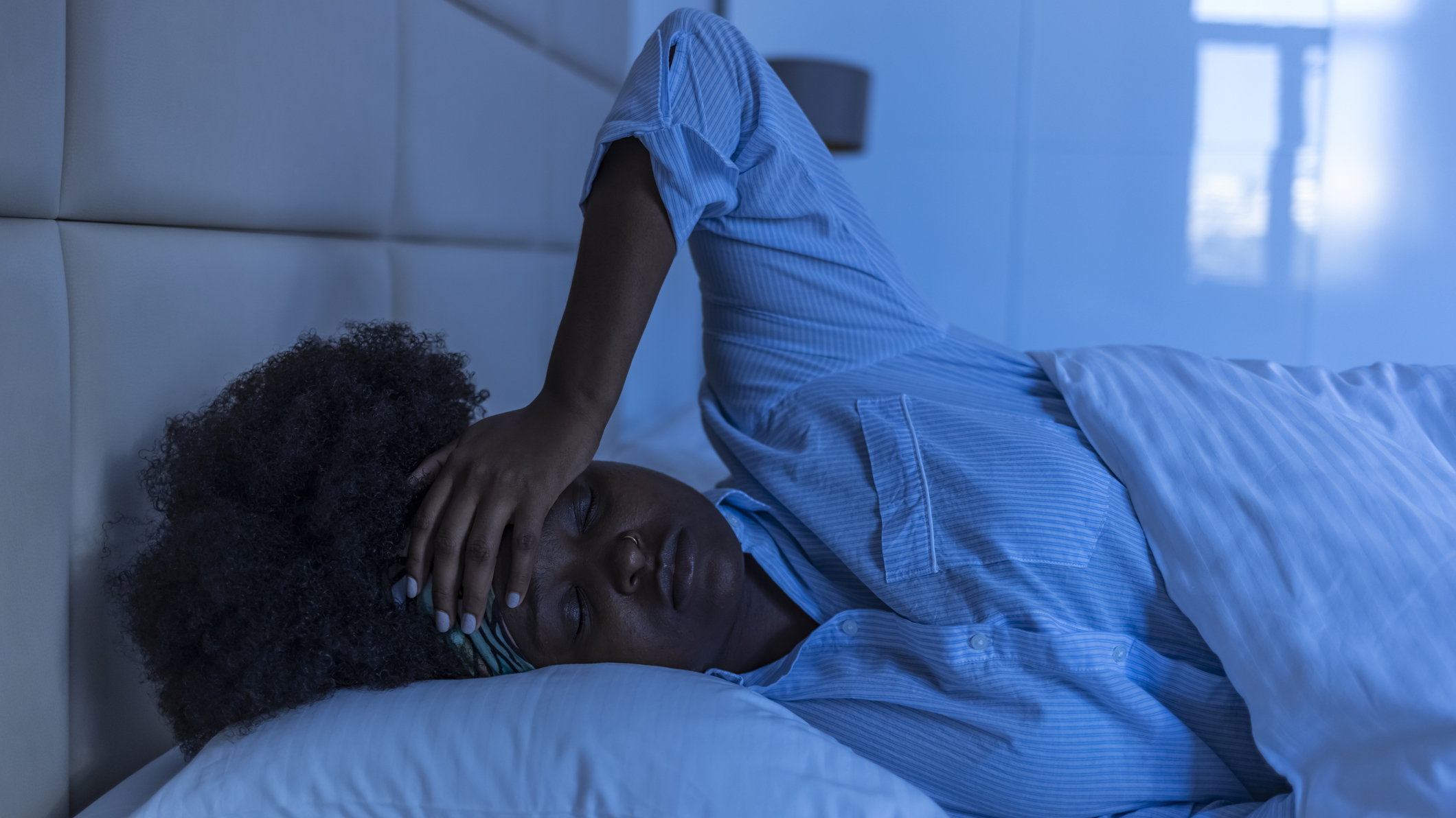 A woman lies in bed at night unable to sleep
