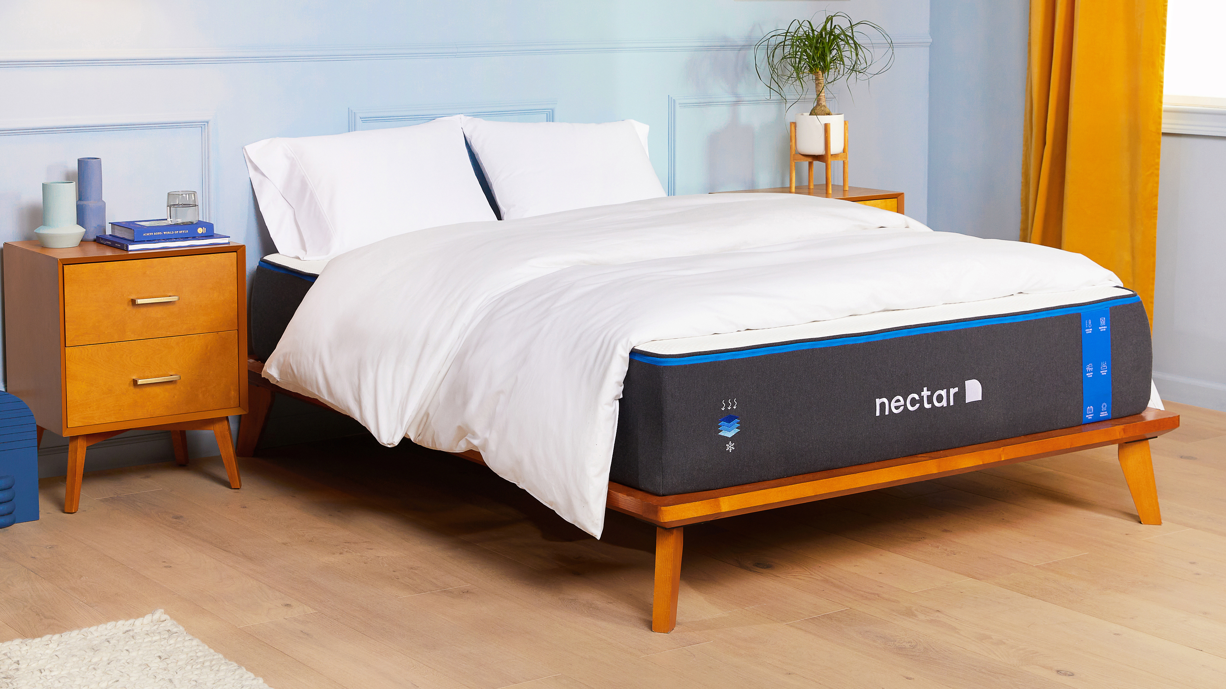 Nectar Memory Foam Mattress shown on a light wooden bed frame and dressed with white pillows and sheets