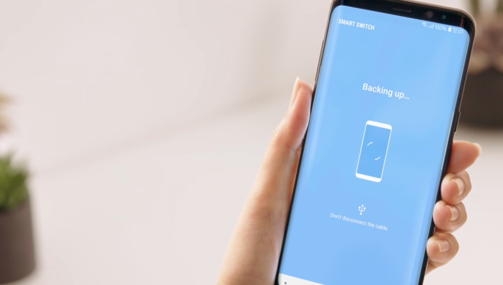A Samsung phone in someone's hand, backing up to Smart Switch