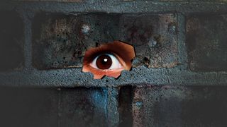 Eye looking through the hole on cracked wall. Spy peeking through hole in brick wall. Spy concept.