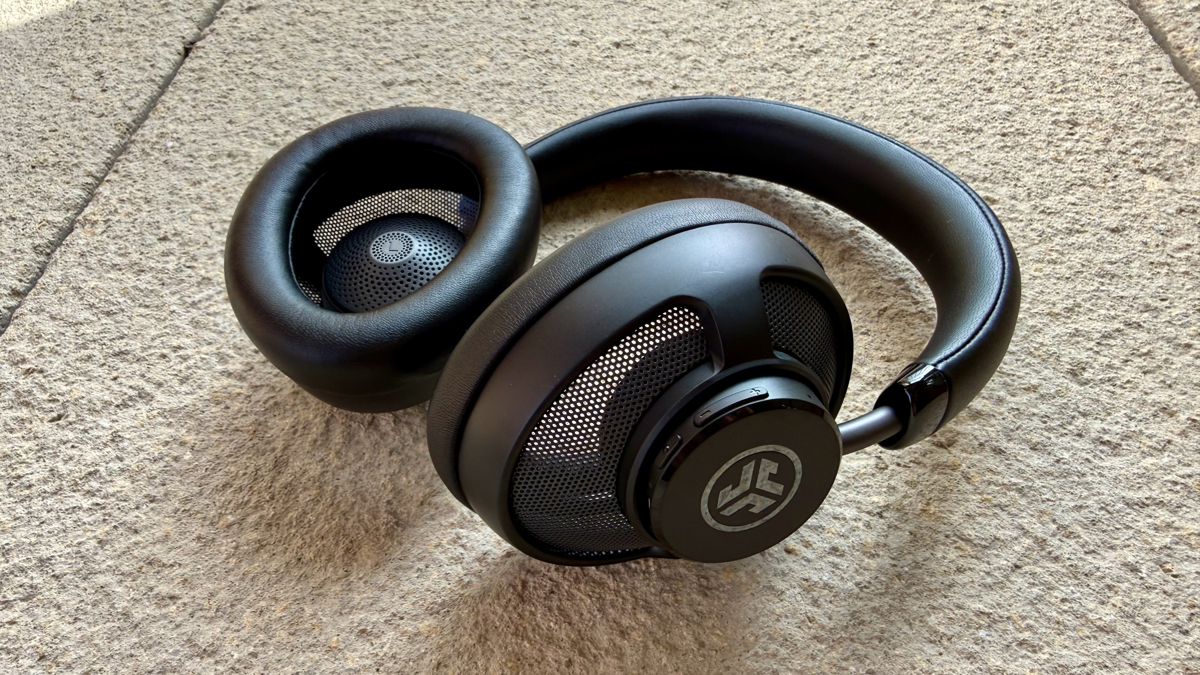 The jlab jbuds open wireless headphones pictured on a stone surface