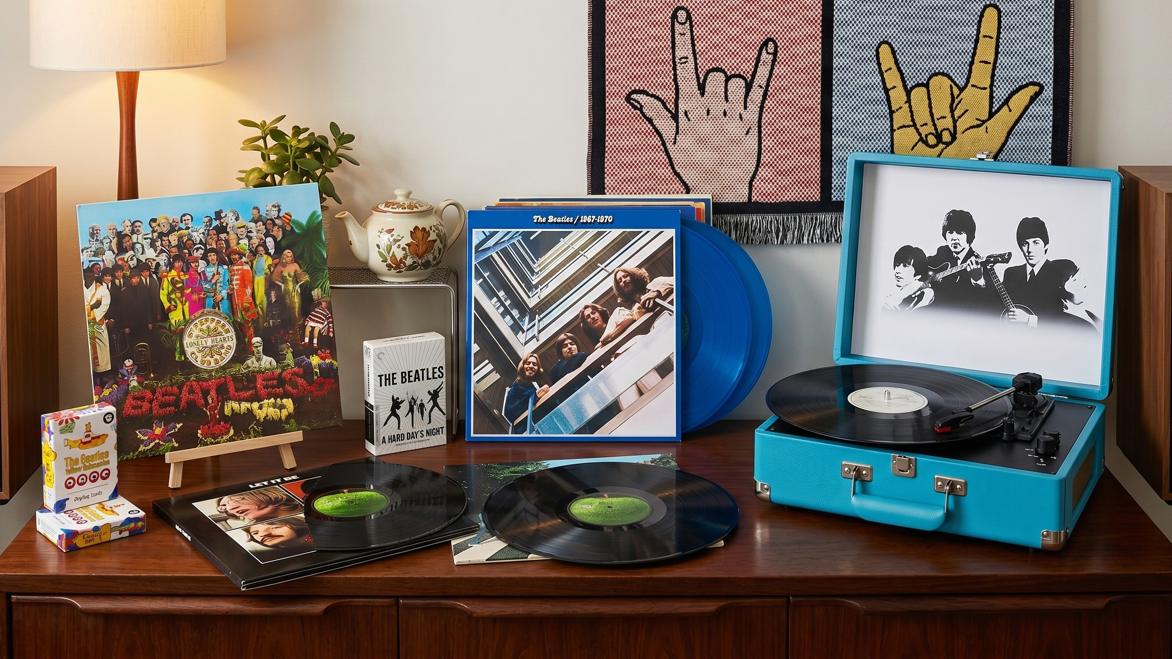 Seveal Beatles vinyl albums on a wooden sideboard, with a Beatles-branded suitcase turntable, plus some Beatles playing cards and A Hard Day's Night on Blu-ray