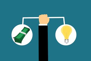 Hand balancing money and a lightbulb