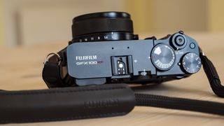 All-black Fujifilm GFX100RF rangefinder-style camera on a wooden table