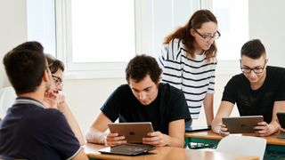 Students using Apple devices in a classroom.