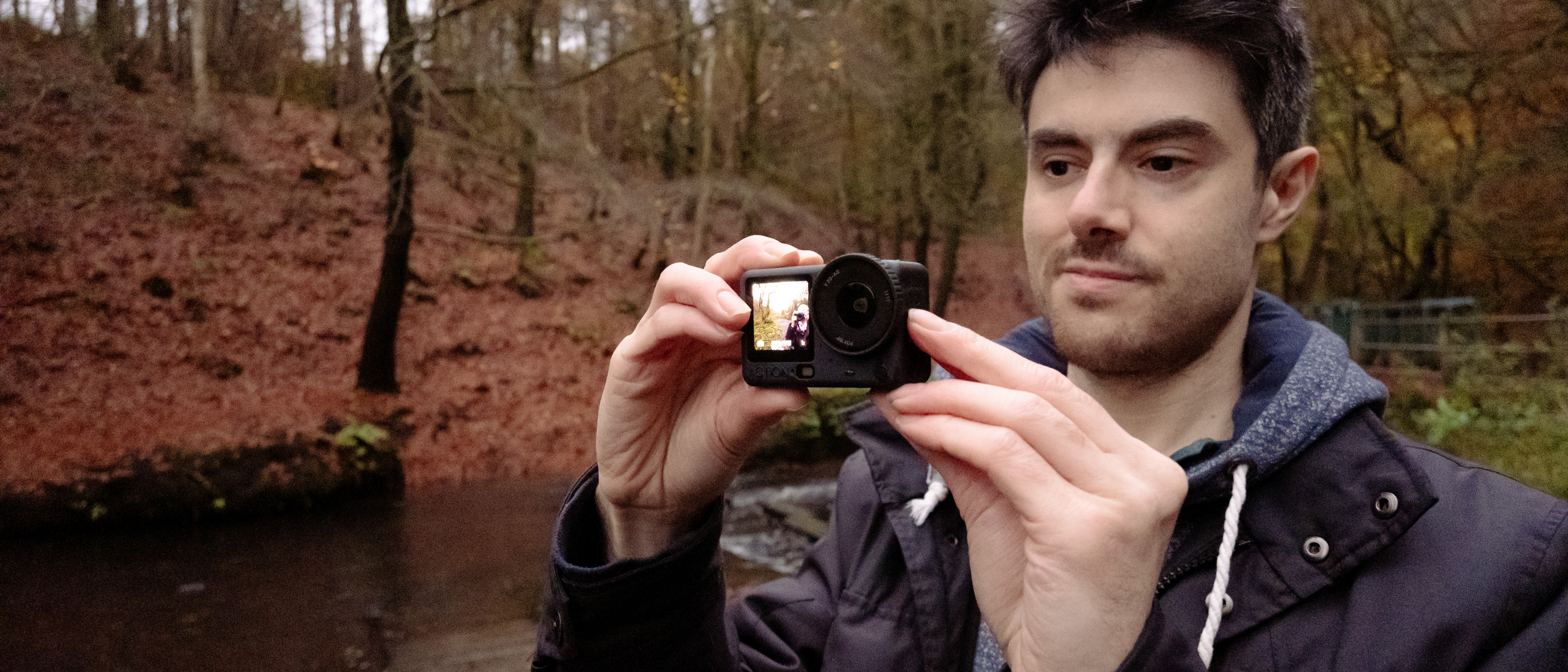 Man holding the DJI Osmo Action 6 action camera in a woodland setting