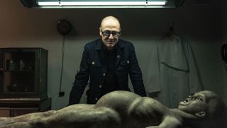 A man standing over the body of an alien in The Alien Autopsy Scandal documentary 2026