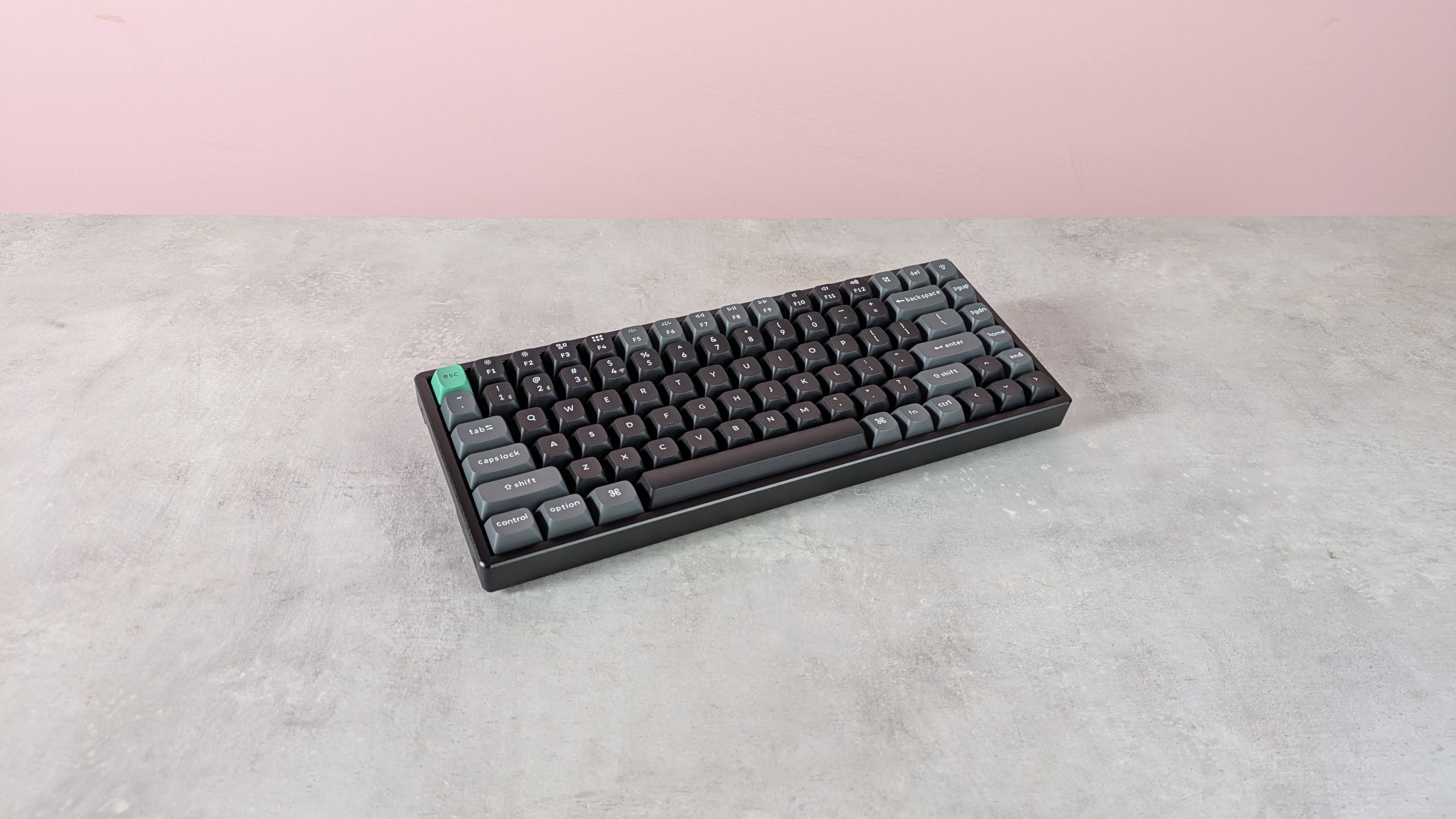 Three-quarter view of Keychron K2 Ultra 8K on a desk with pink wall in background
