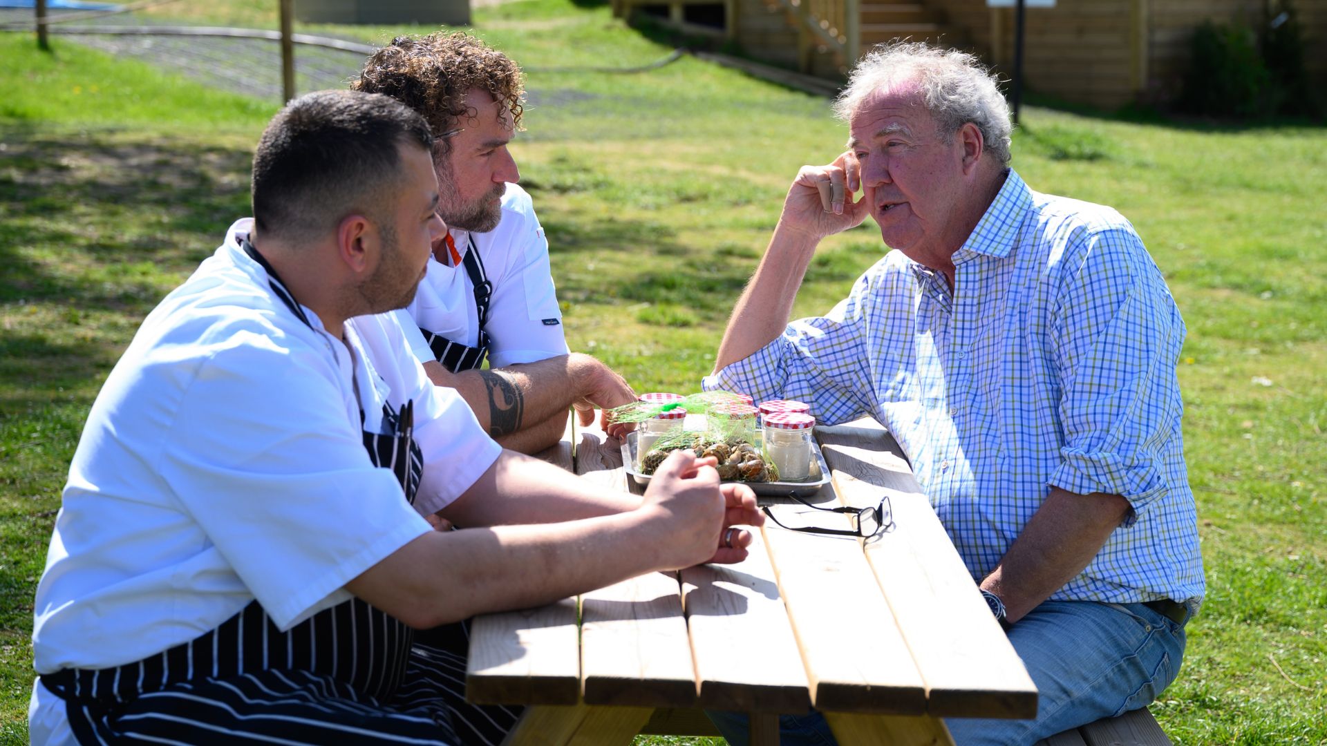 Jeremy talks to two chefs across a picnic table
