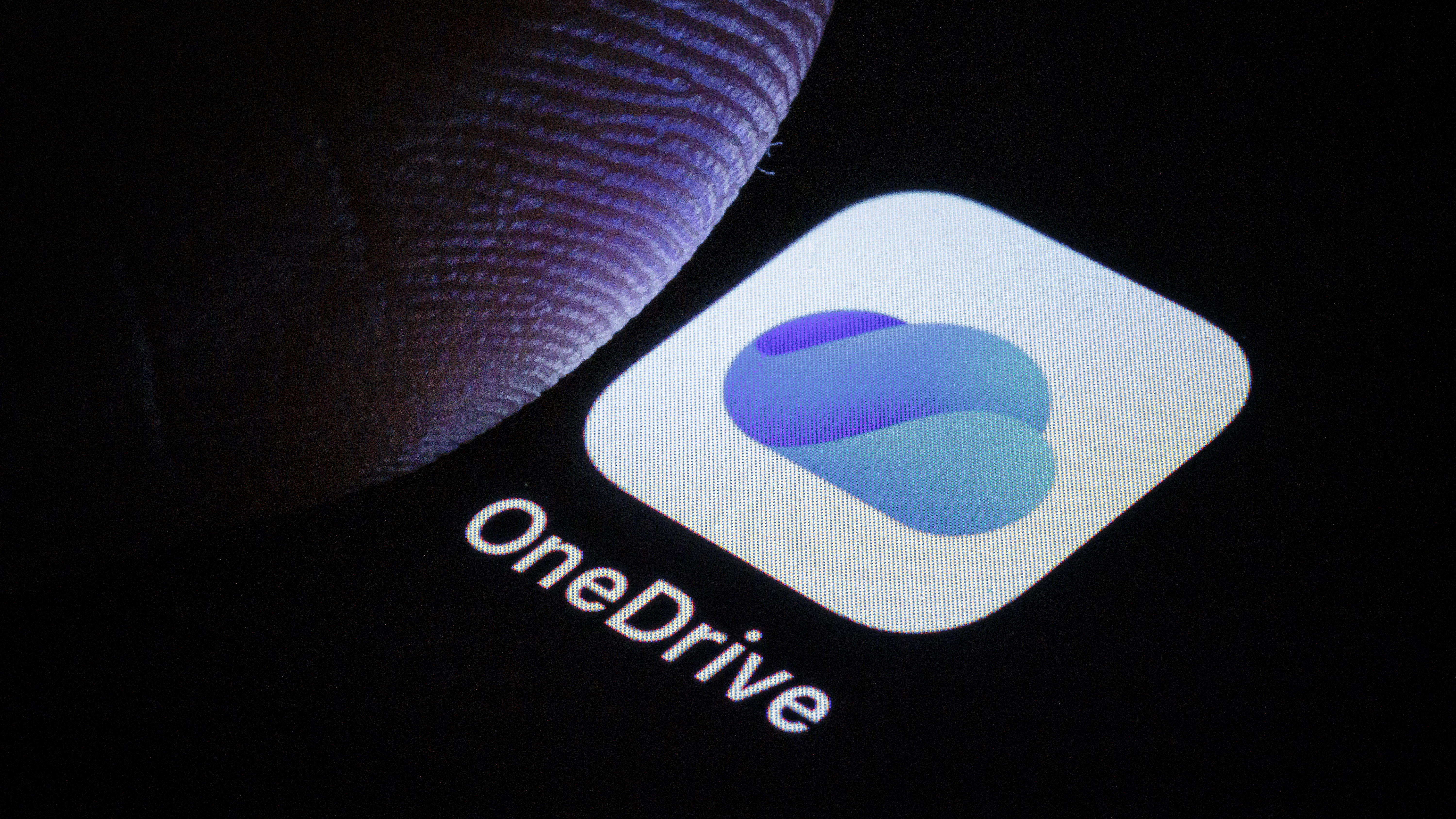 A thumb over the OneDrive logo on a phone