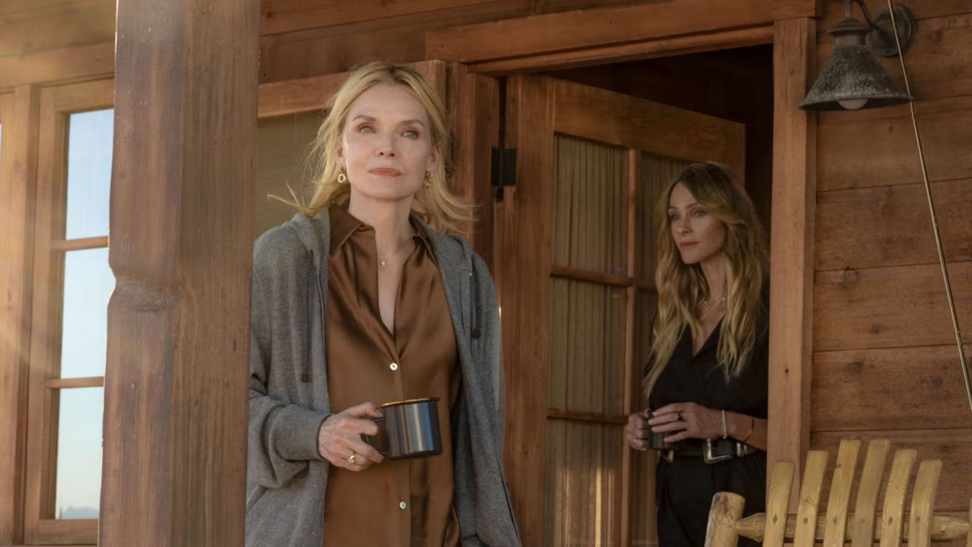 Two women stand on a porch holding mugs