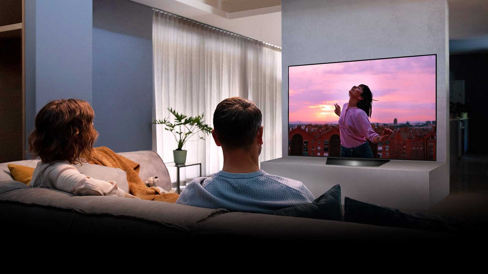 A couple watching an LG BX OLED while sitting on a sofa