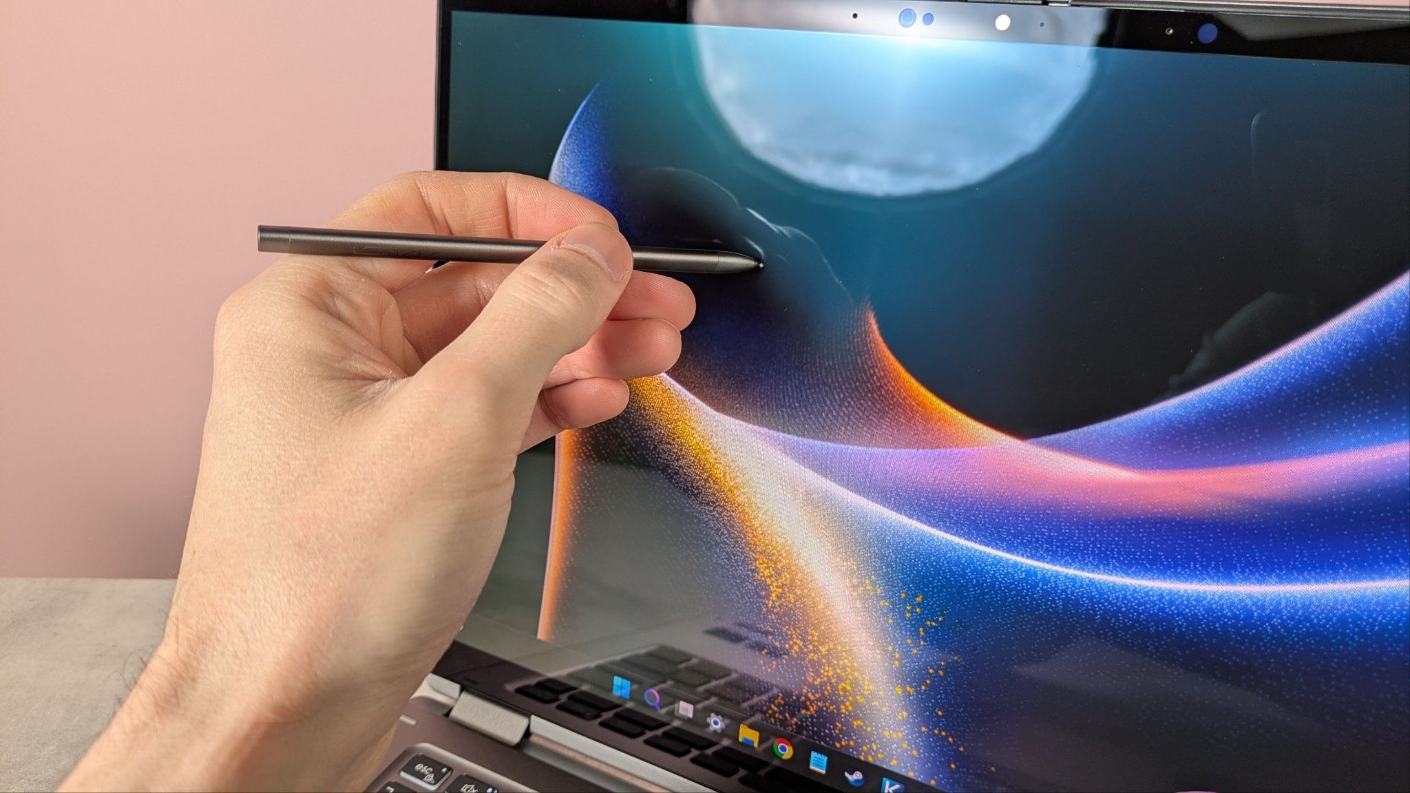 Hand holding MSI Nano Pen against display of MSI Prestige 14 Flip AI+, with pink wall in background