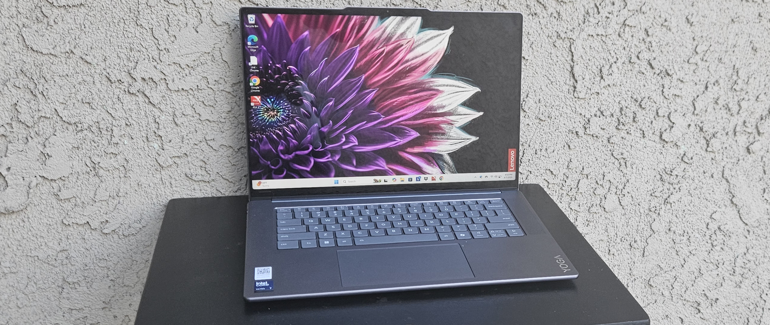 Lenovo Yoga Slim 7i Aura Edition powered on resting on a small black table