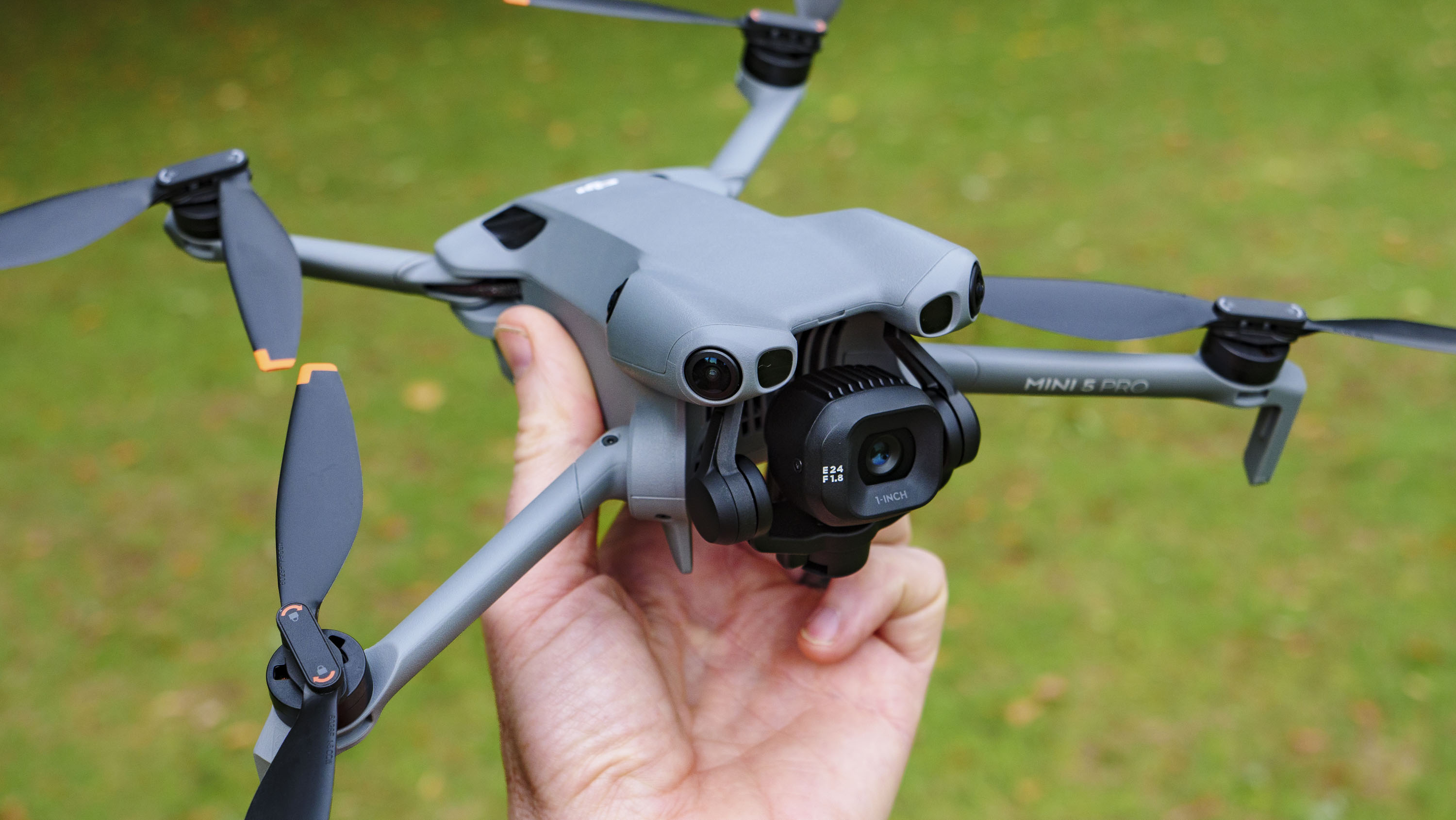 DJI Mini 5 Pro in pilot's hand, grass background