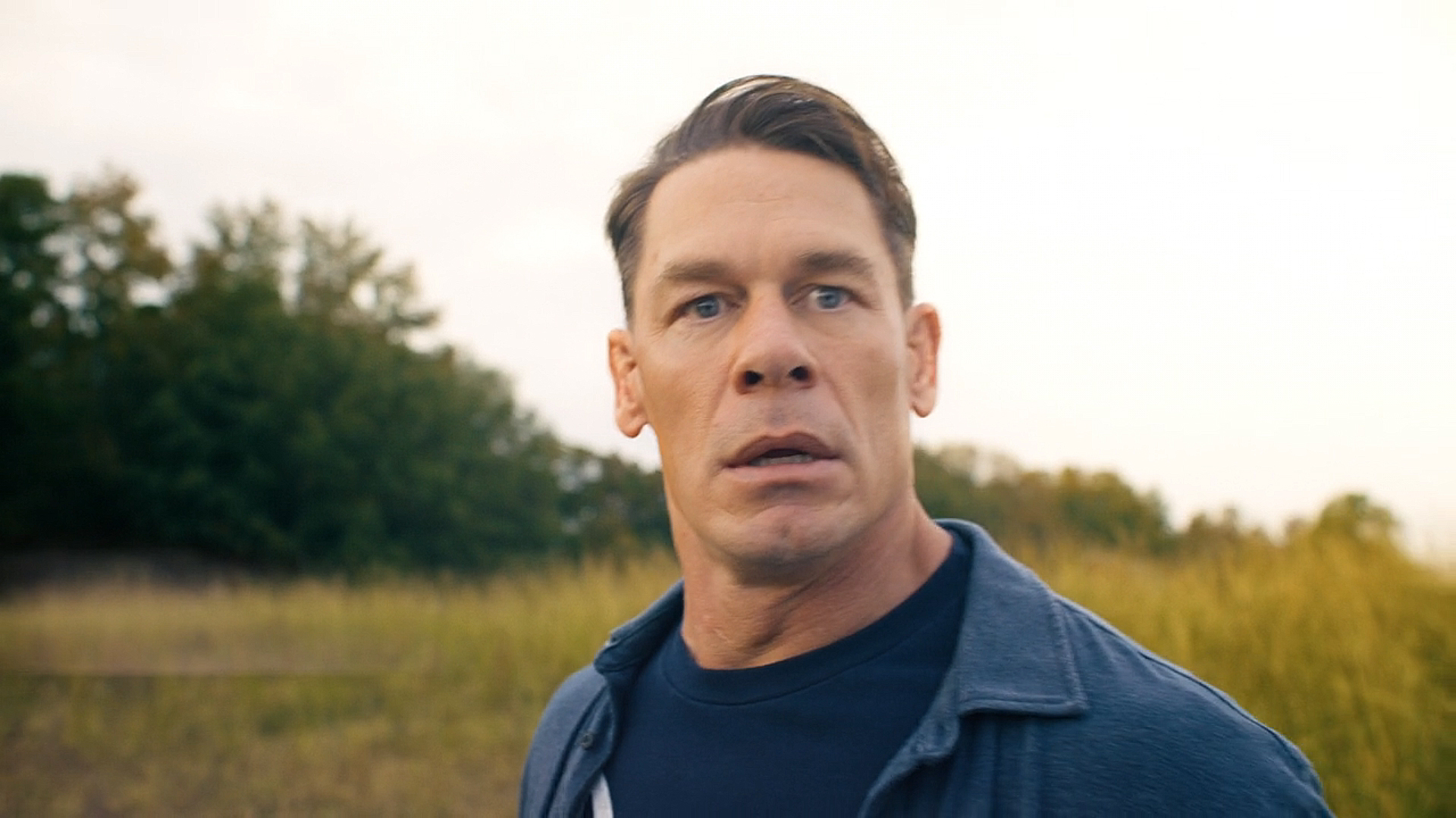 A close up of Chris Smith looking worried as he stands in an open field in Peacemaker season 2 episode 8