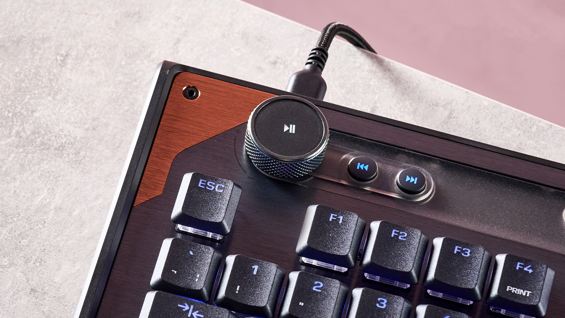 A closeup of the Turtle Beach Command Series KB7's volume knob, media buttons and wood effect inlay.